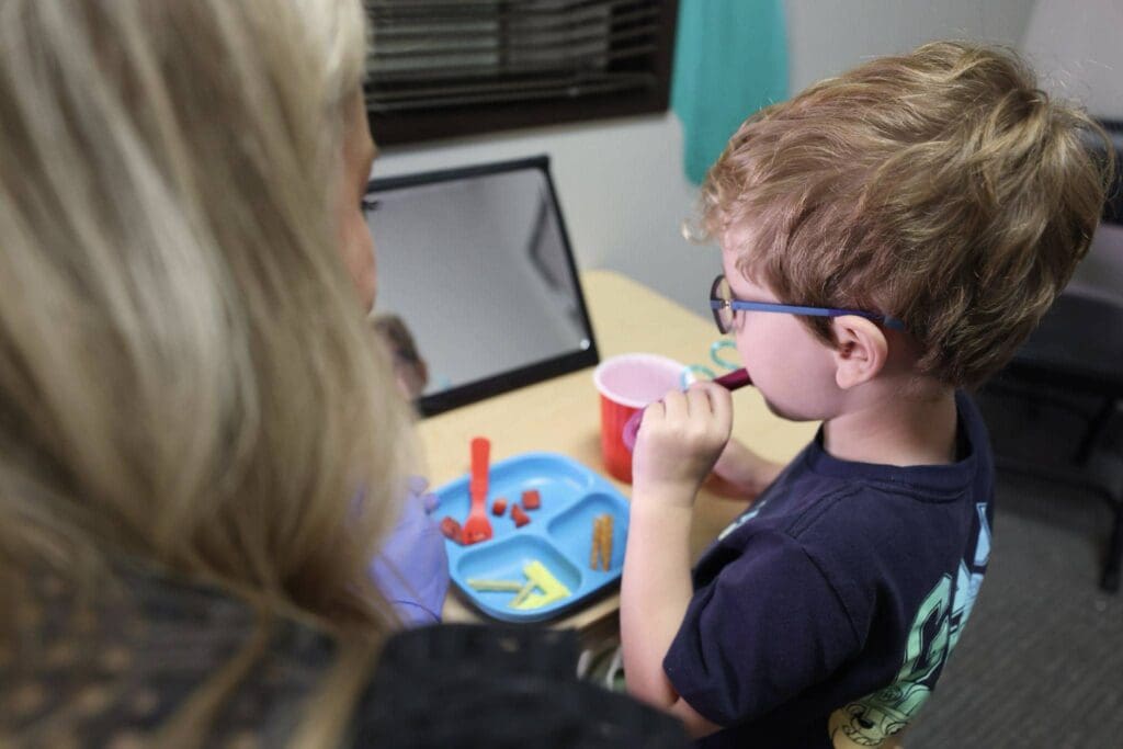 A boy with a feeding and swallowing disorder works on feeding and swallowing therapy at Bliss Speech and Hearing Services.